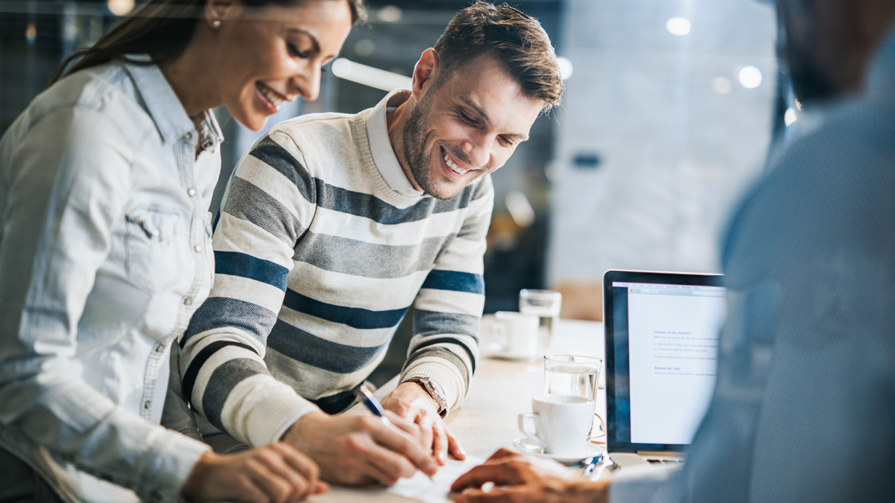 Zwei Berater am Tisch besprechen sich und schreiben etwas