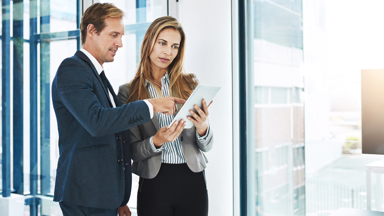 Zwei Personen besprechen sich stehend mit Tablet in der Hand