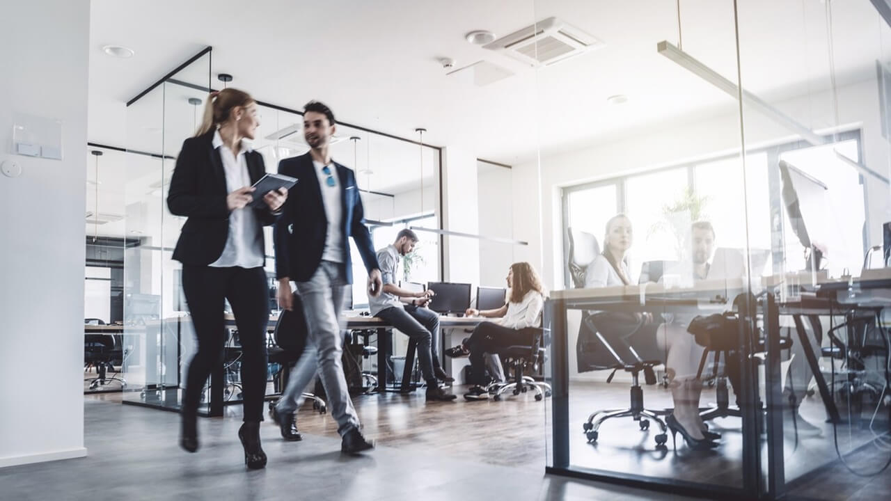 Zwei Personen laufen durch modernes Büro